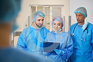 Medical team discussing while standing in hospital