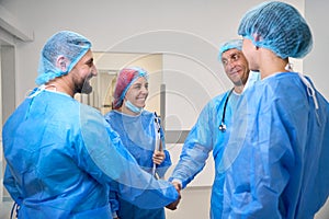 Medical team of doctors surgeons handshaking
