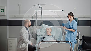 Medical team doing consultation with old patient in bed