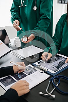 Medical team having a meeting with doctors in white lab coats and surgical scrubs seated at a table discussing a patients working