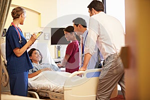 Medical Team Meeting Around Female Patient In Hospital Room