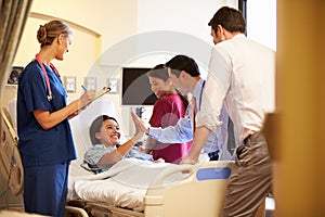 Medical Team Meeting Around Female Patient In Hospital Room