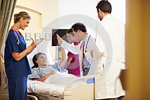 Medical Team Meeting Around Female Patient In Hospital Room