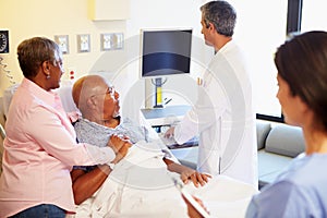 Medical Team Meeting With Senior Couple In Hospital Room