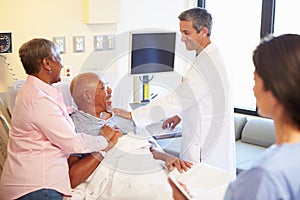 Medical Team Meeting With Senior Couple In Hospital Room