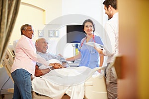 Medical Team Meeting With Senior Couple In Hospital Room