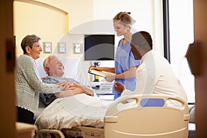 Medical Team Meeting With Senior Couple In Hospital Room