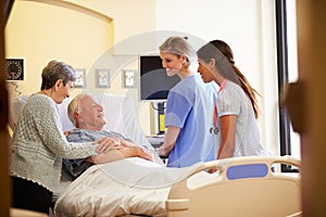 Medical Team Meeting With Senior Couple In Hospital Room