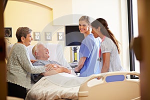 Medical Team Meeting With Senior Couple In Hospital Room