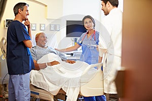 Medical Team Meeting With Senior Man In Hospital Room