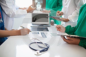 Medical team meeting with surgical surgeon in white coats and surgical team discussing patient condition documenting successful