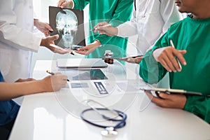 Medical team meeting with surgical surgeon in white coats and surgical team discussing patient condition documenting successful