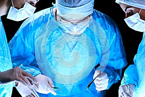 Medical team performing operation. Group of surgeon at work in operating theatre toned in blue