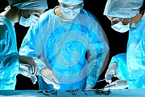 Medical team performing operation. Group of surgeon at work in operating theatre toned in blue