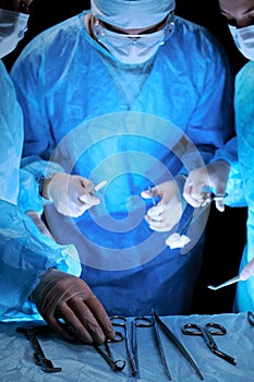 Medical team performing operation. Group of surgeon at work in operating theatre toned in blue