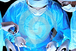 Medical team performing operation. Group of surgeon at work in operating theatre toned in blue