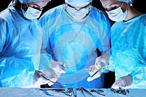 Medical team performing operation. Group of surgeon at work in operating theatre toned in blue