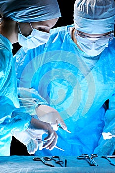 Medical team performing operation. Group of surgeon at work in operating theatre toned in blue