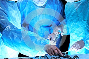 Medical team performing operation. Group of surgeon at work in operating theatre toned in blue