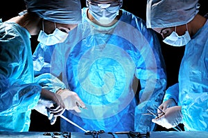 Medical team performing operation. Group of surgeon at work in operating theatre toned in blue