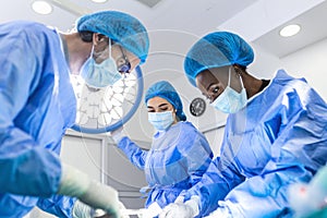 Medical team performing operation. Group of surgeon at work in operating theatre toned in blue. Doctor operation in operation room