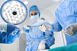 Medical Team Performing Surgical Operation in Bright Modern Operating Room. Group of surgeons at work in operating theater toned