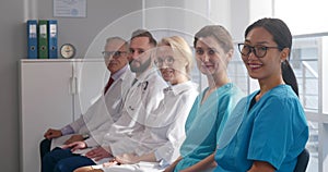 Medical team sitting in row and looking at camera