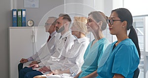 Medical team sitting in row and looking at camera