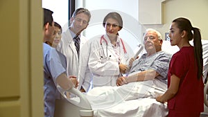 Medical Team Talking To Senior Male Patient In Hospital