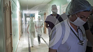 Medical team walking together along hospital corridor. Group of doctors in hurry for surgery or for examination of