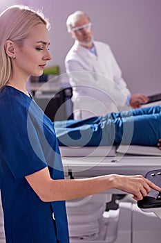 Medical technical assistant performing radiological scan of patient with magnetic resonance tomography MRI