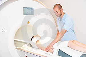 Medical technical assistant preparing scan of shoulder with MRI