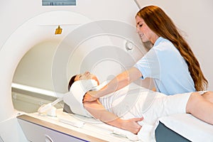 Medical technical assistant preparing scan of shoulder with MRI