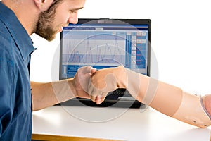 Medical technician looks over prosthetic arm. Computer-controlled adjusting.
