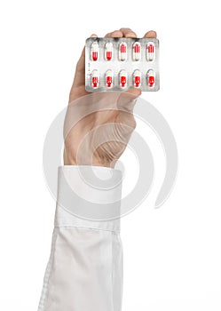 Medical theme: doctor's hand holding a red capsule for health on a white background isolated