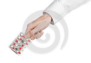 Medical theme: doctor's hand holding a red capsule for health on a white background isolated