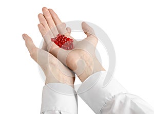 Medical theme: doctor's hand holding a red capsule for health on a white background isolated