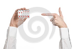 Medical theme: doctor's hand holding a red capsule for health on a white background isolated