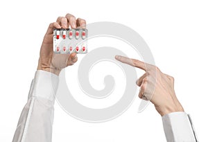 Medical theme: doctor's hand holding a red capsule for health on a white background isolated