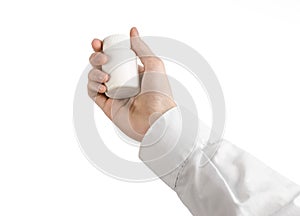 Medical theme: doctor's hand holding a white empty jar of pills on a white background