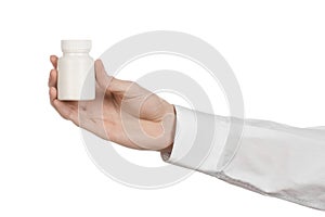Medical theme: doctor's hand holding a white empty jar of pills on a white background
