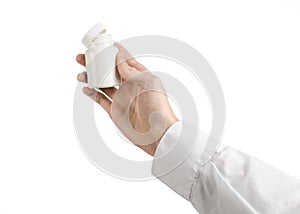Medical theme: doctor's hand holding a white empty jar of pills on a white background