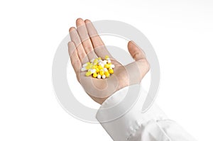 Medical theme: doctor's hand holding a yellow capsule for health on a white background isolated