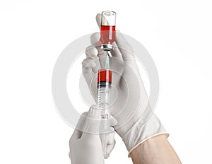 Medical theme: doctor's hand in a white glove holding a red vial of liquid for injection isolated on white background