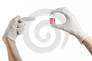 Medical theme: doctor's hand in a white glove holding a red vial of liquid for injection isolated on white background