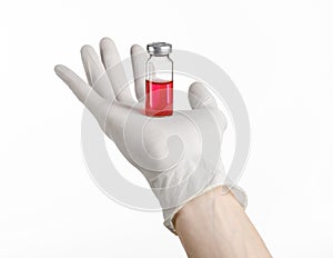 Medical theme: doctor's hand in a white glove holding a red vial of liquid for injection isolated on white background