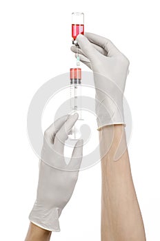 Medical theme: doctor's hand in a white glove holding a red vial of liquid for injection isolated on white background