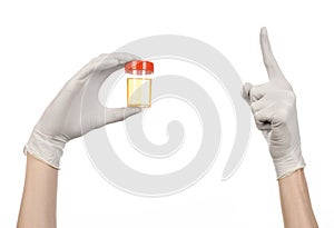 Medical theme: doctor's hand in white gloves holding a transparent container with the analysis of urine on a white background
