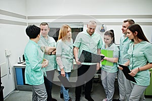 Medical theme.Observation room with a computer tomograph. The group of doctors meeting in the mri office and looking at x-ray at