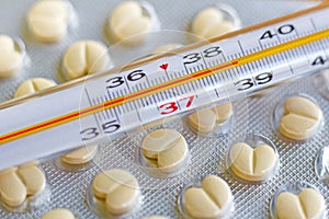 Medical thermometer on the background of tablets in a blister pack closeup